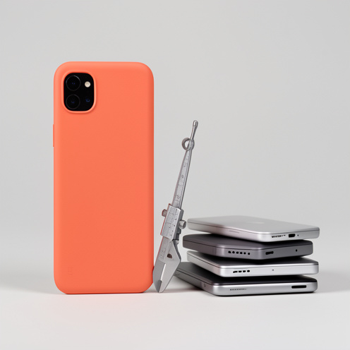 Smartphone compatto color corallo accanto a un calibro e ad altri dispositivi per rappresentare dimensioni e convenienza.