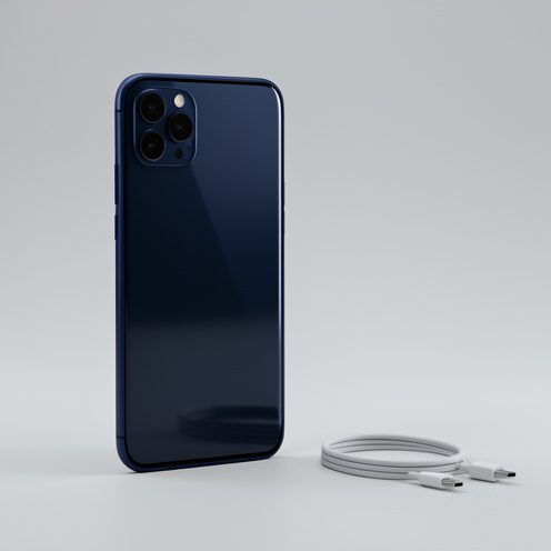 Smartphone premium bleu nuit présenté debout sur une surface gris clair, avec deux caméras arrière et un câble de charge à côté.