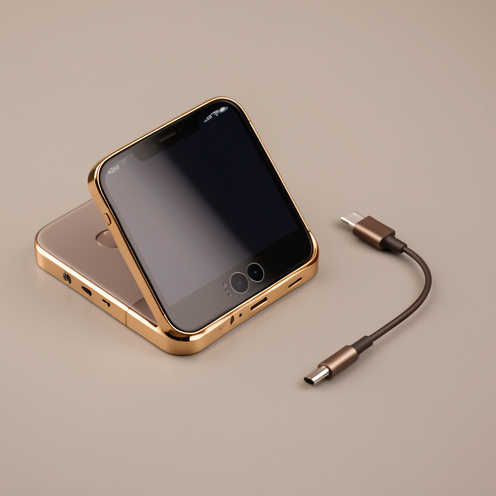 Smartphone haut de gamme d’ancienne génération avec cadre doré, écran noir et double caméra arrière, photographié sur un fond gris chaleureux.